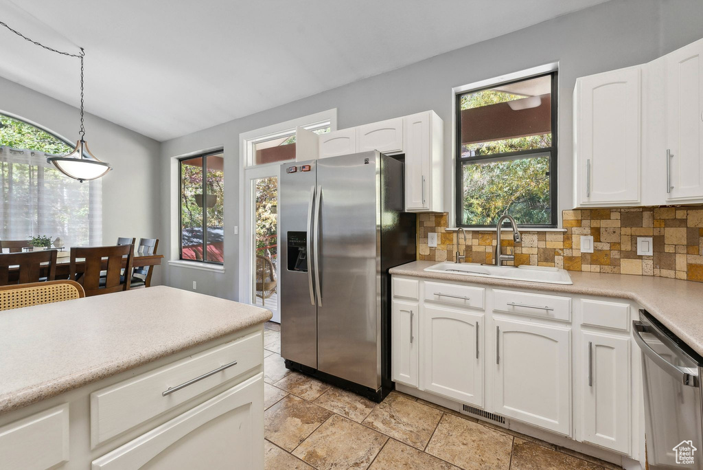 Kitchen featuring sink, decorative light fixtures, white cabinetry, appliances with stainless steel finishes, and a healthy amount of sunlight