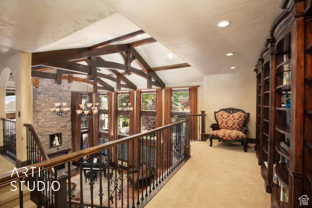 Corridor with vaulted ceiling with beams, carpet, and a chandelier