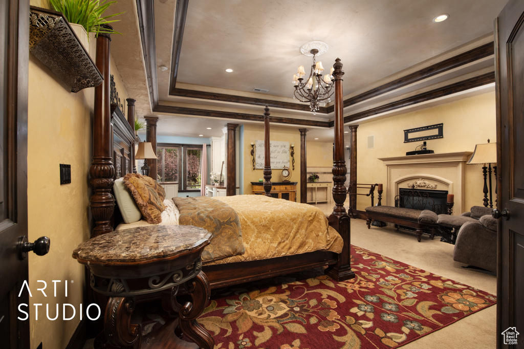 Carpeted bedroom with a raised ceiling, ornate columns, ornamental molding, and a chandelier
