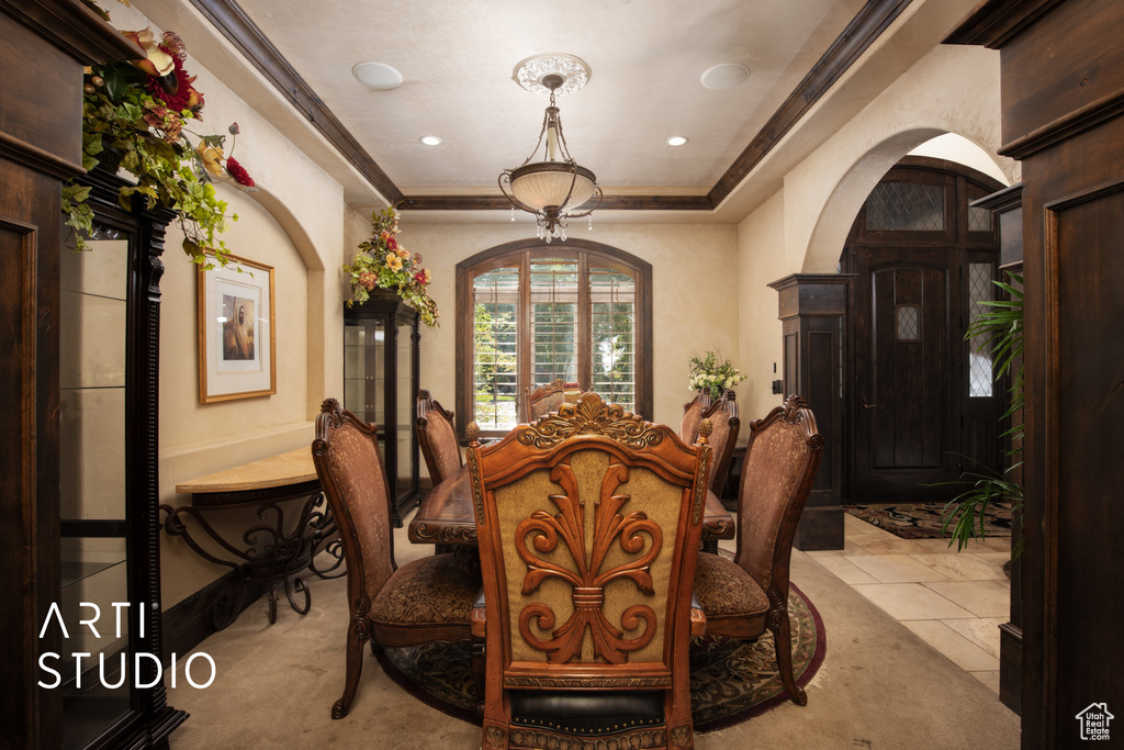 Dining area featuring ornamental molding, a raised ceiling, and light tile patterned floors