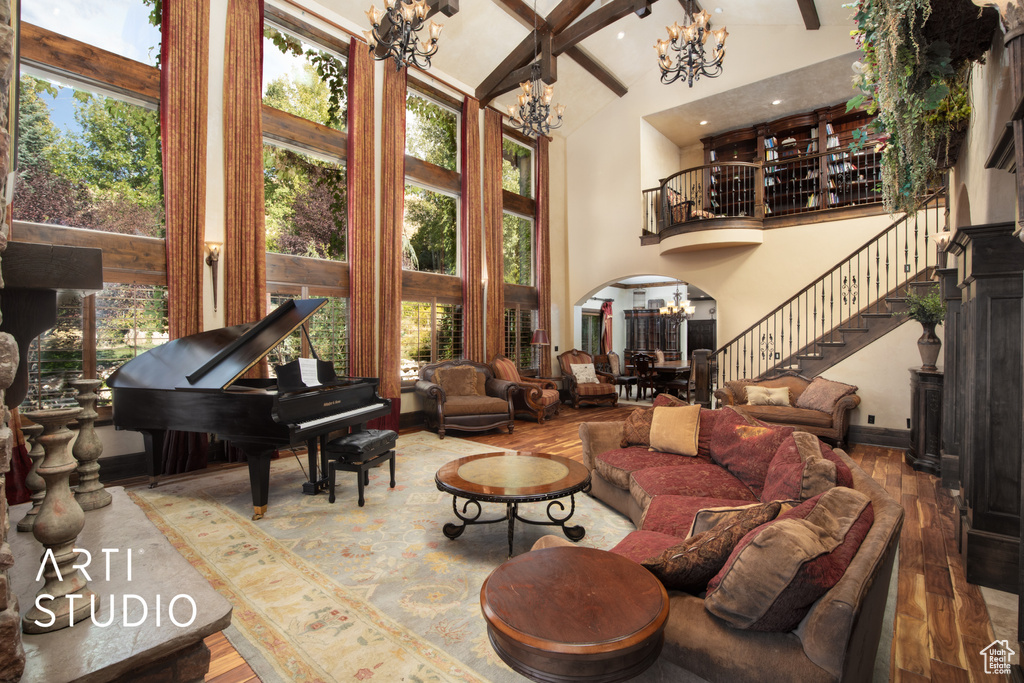 Living room with a notable chandelier, hardwood / wood-style flooring, beam ceiling, and high vaulted ceiling