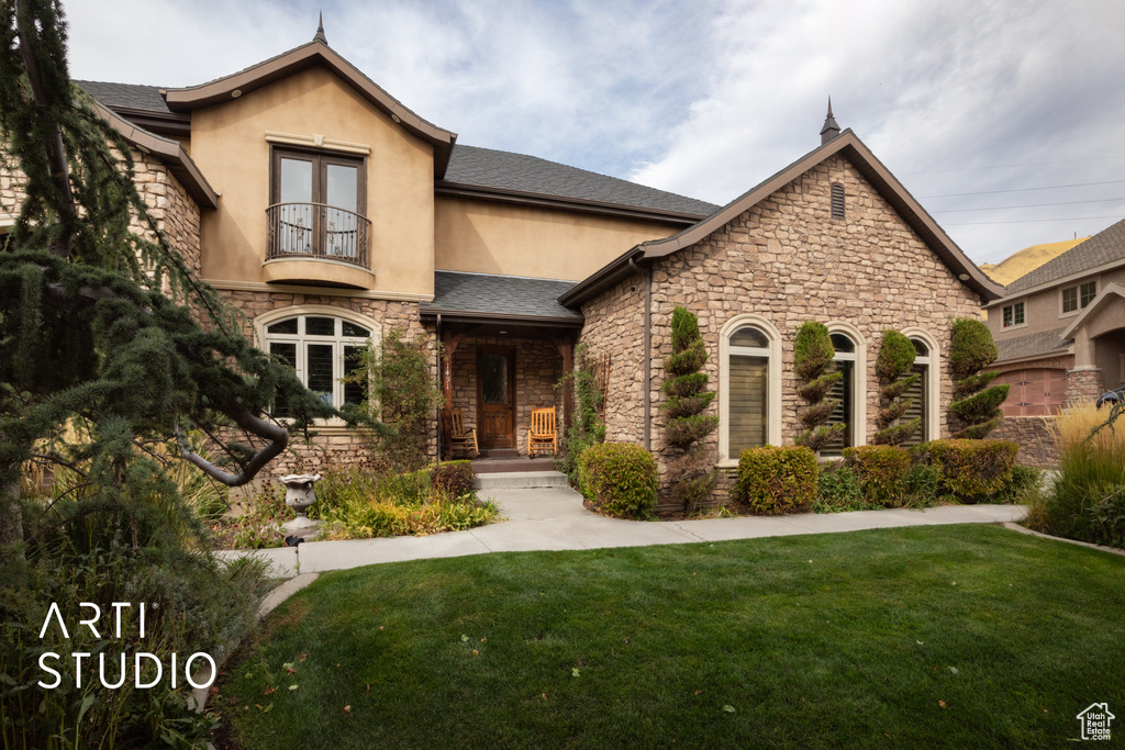 View of front facade featuring french doors, a front yard, and a balcony