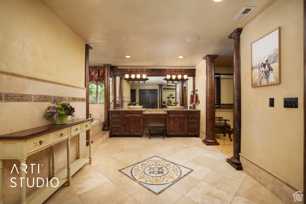 Bathroom featuring ornate columns, tile patterned floors, and vanity