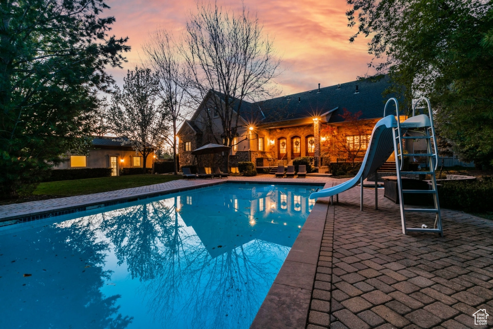 Pool at dusk with a water slide and a patio