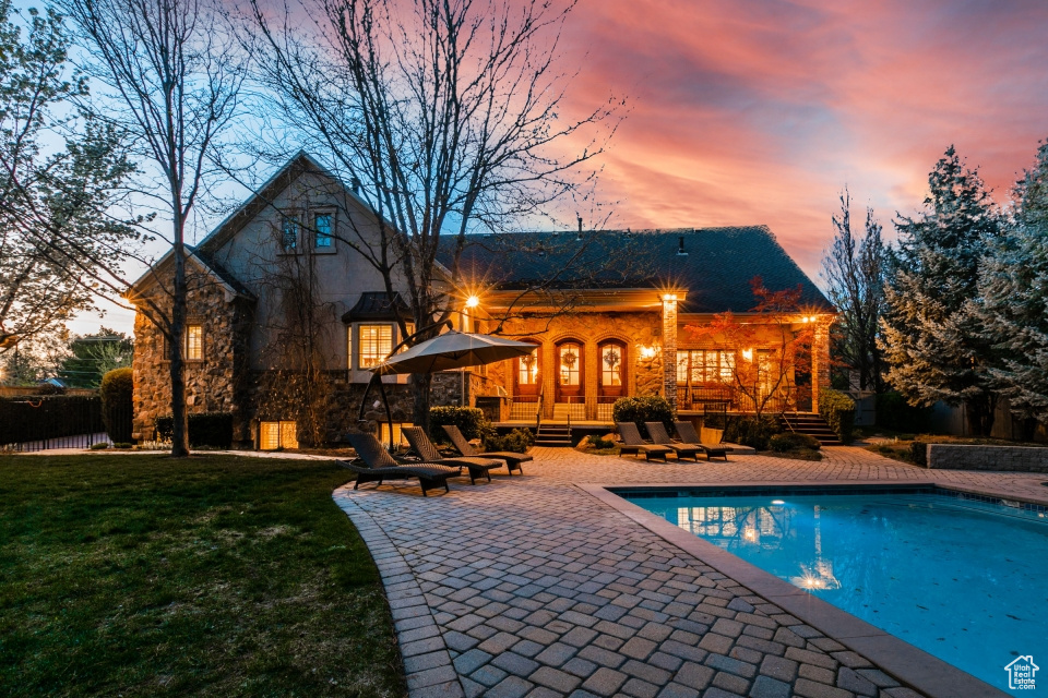 Back house at dusk with french doors, a patio, and a yard