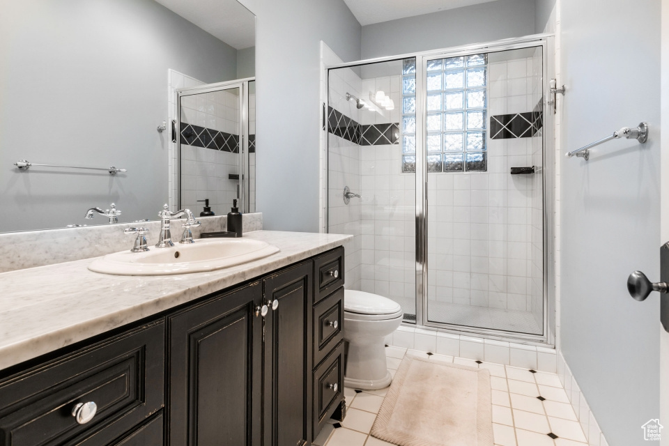 Bathroom with tile patterned flooring, vanity, walk in shower, and toilet