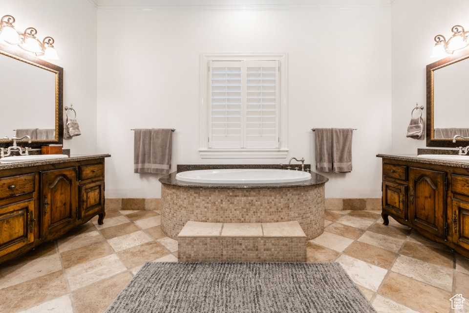 Bathroom with crown molding, a relaxing tiled tub, and vanity