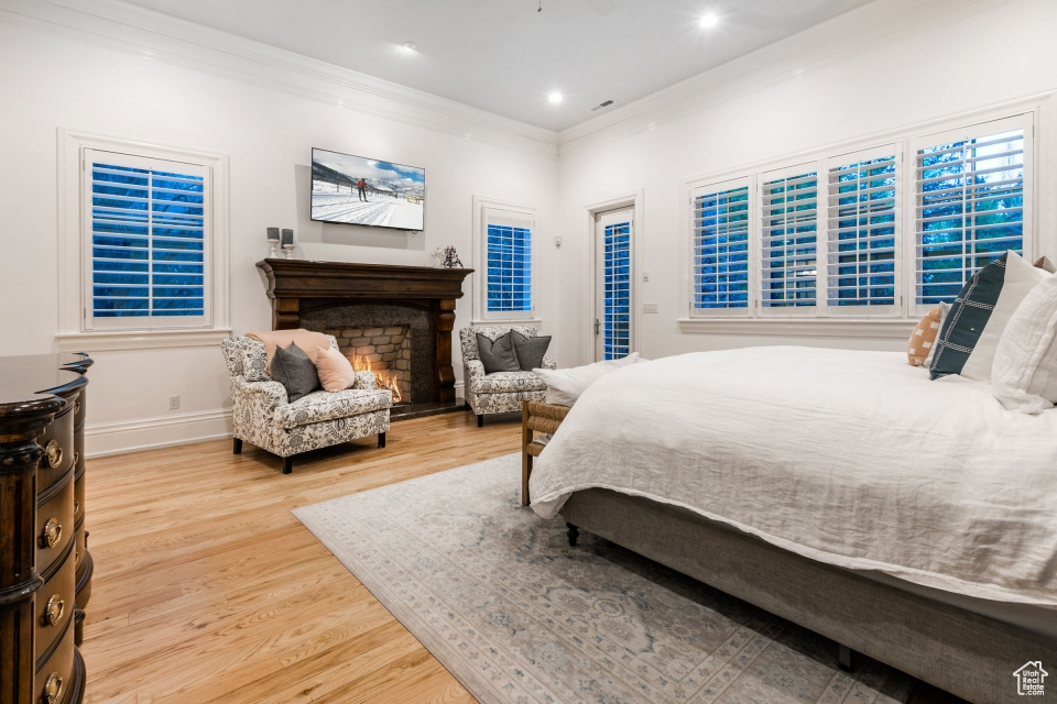 Bedroom with wood-type flooring, ornamental molding, and access to exterior