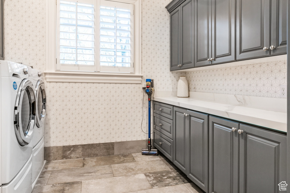 Clothes washing area featuring cabinets and washing machine and dryer