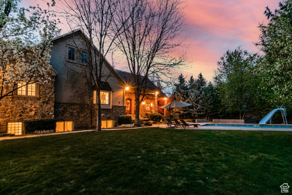 Back house at dusk with a yard and a patio area