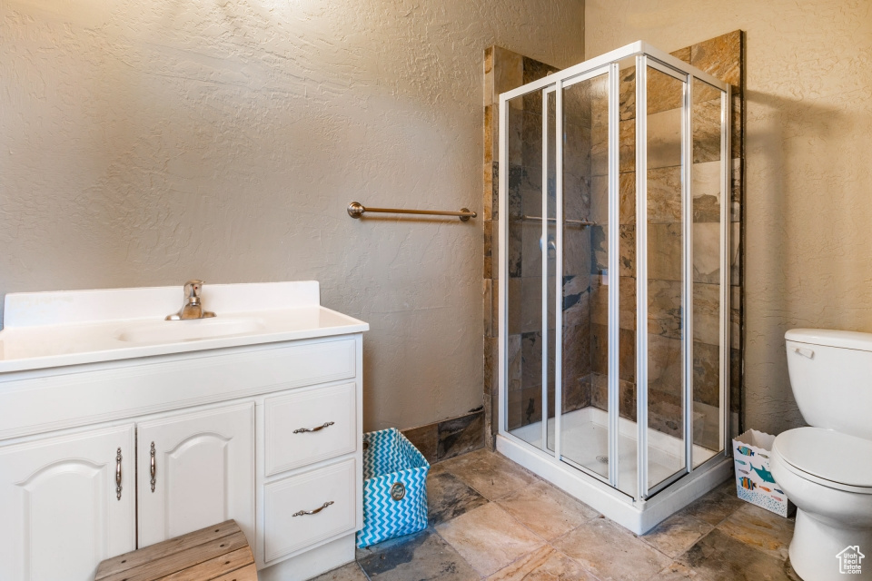 Bathroom featuring walk in shower, vanity, and toilet