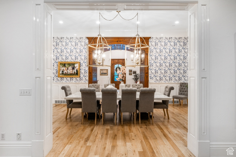 Dining space featuring an inviting chandelier, ornamental molding, and hardwood / wood-style flooring