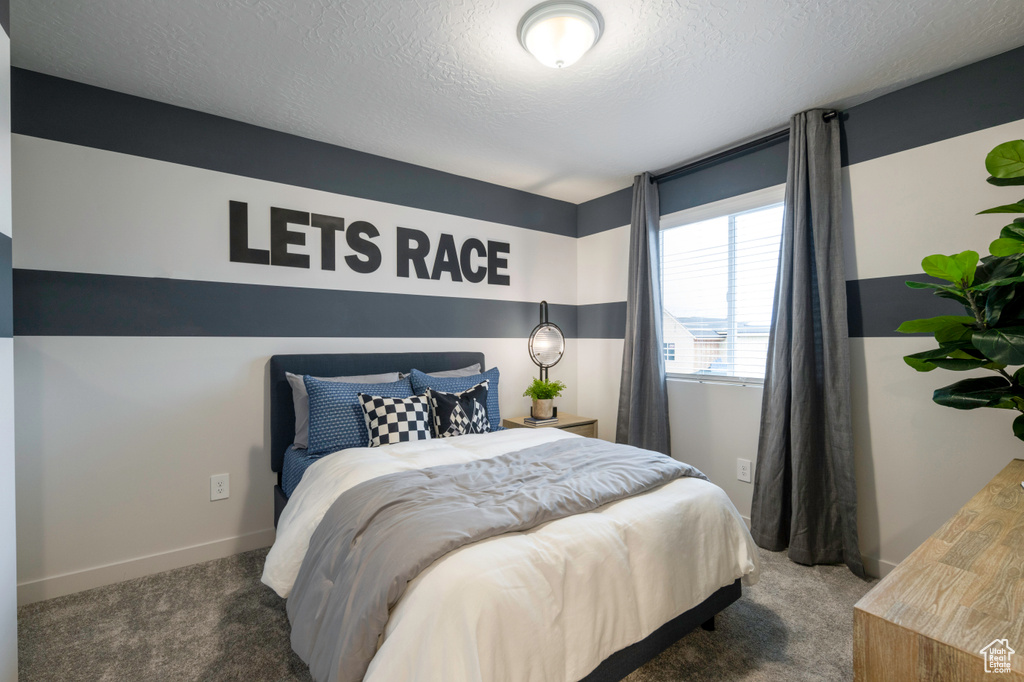 Bedroom with dark carpet and a textured ceiling