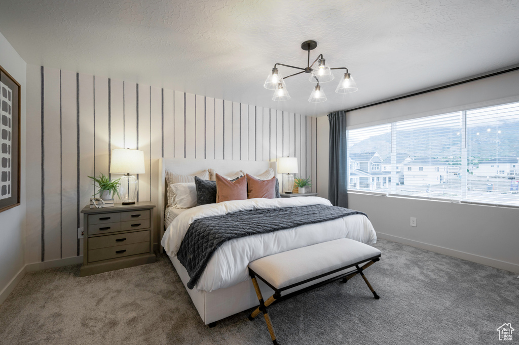 Carpeted bedroom featuring an inviting chandelier and a textured ceiling