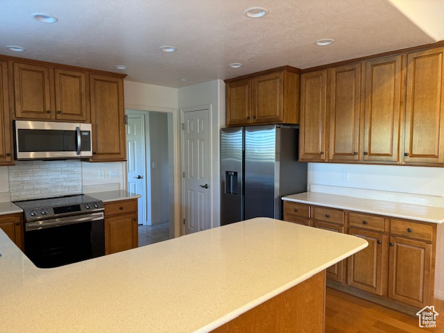 Kitchen with stainless steel appliances, decorative backsplash, and light hardwood / wood-style flooring