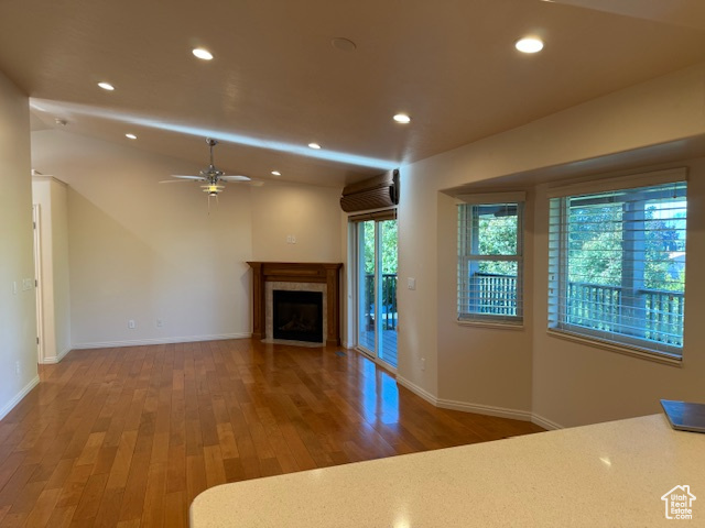 Unfurnished living room with ceiling fan, a tile fireplace, and hardwood / wood-style floors