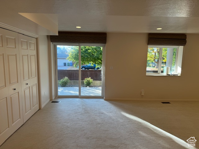 Carpeted spare room featuring a textured ceiling and plenty of natural light