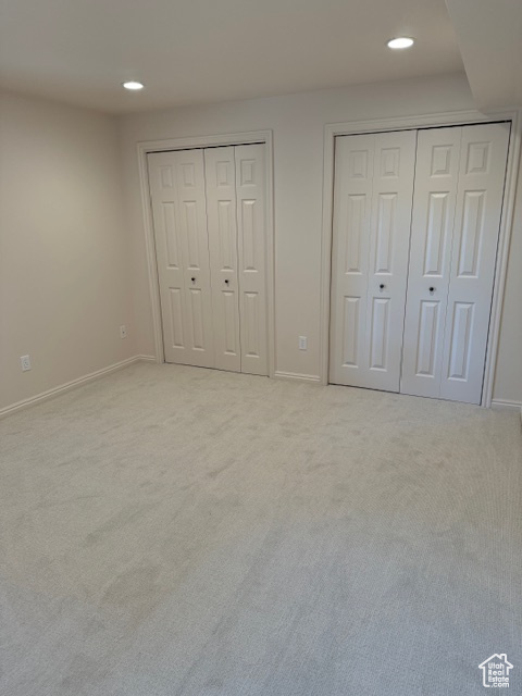 Unfurnished bedroom with light carpet and two closets