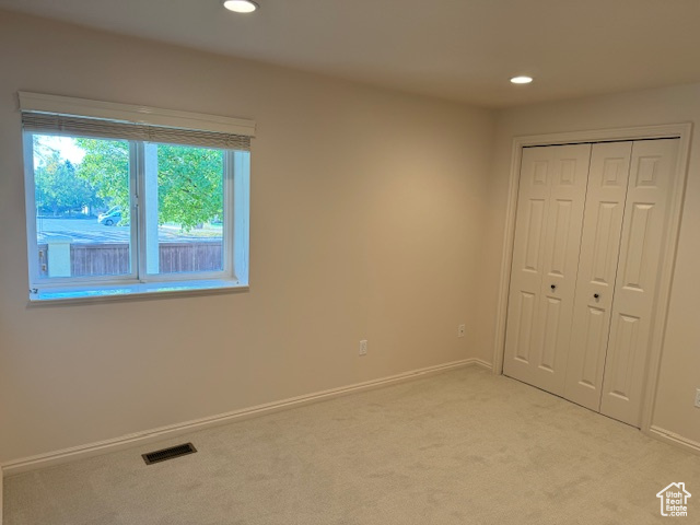 Unfurnished bedroom featuring a closet and light carpet