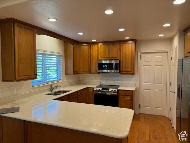 Kitchen with kitchen peninsula, light hardwood / wood-style floors, sink, and stainless steel appliances
