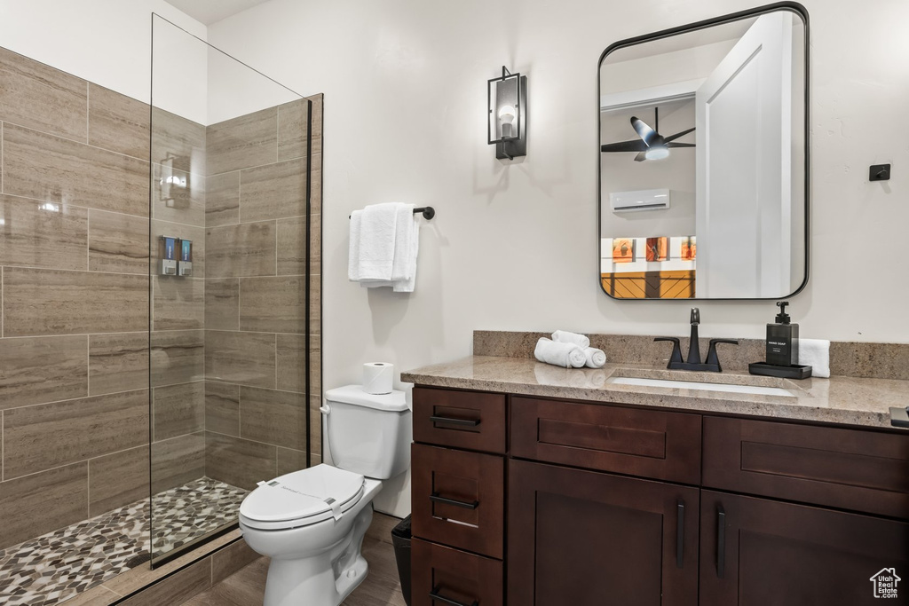 Bathroom with ceiling fan, vanity, toilet, and a shower with door