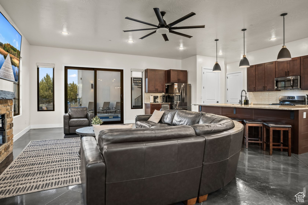 Living room with sink, ceiling fan, and a stone fireplace