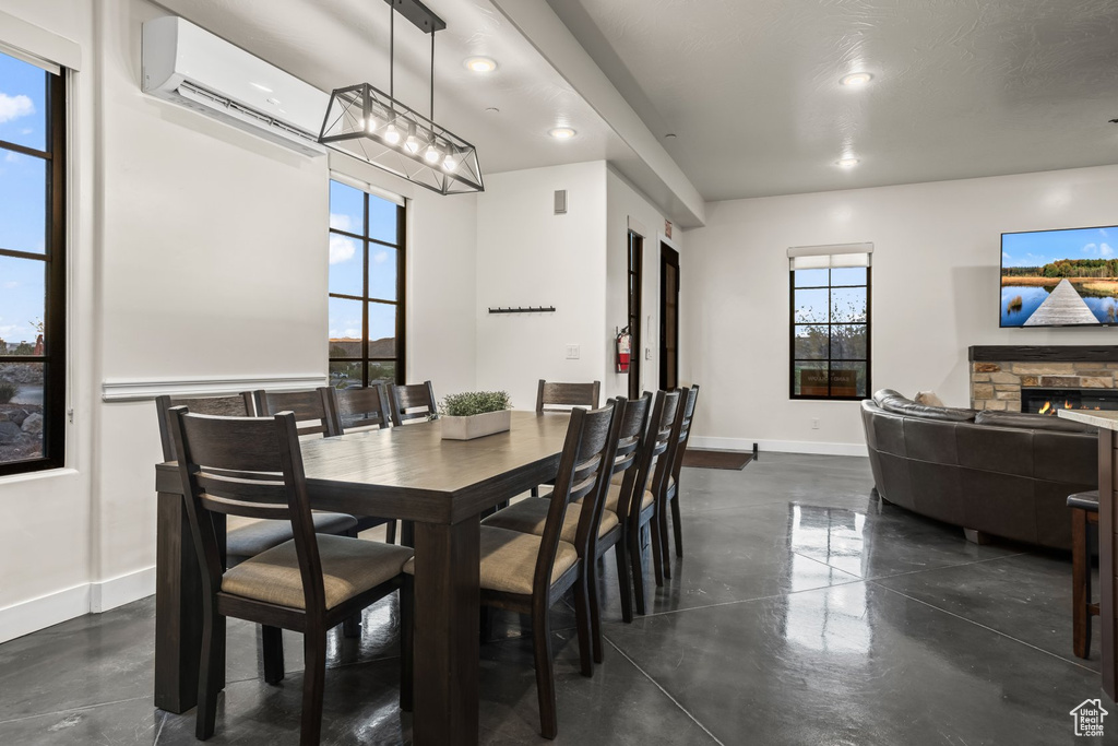 Dining area with a stone fireplace, plenty of natural light, and an AC wall unit