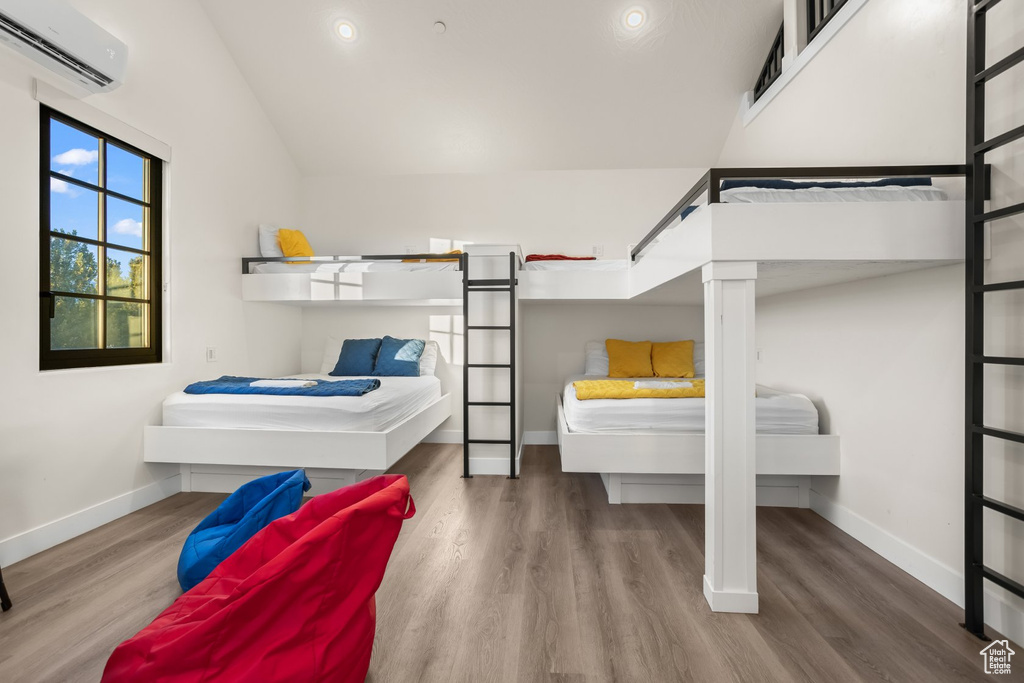 Bedroom with wood-type flooring, lofted ceiling, and a wall mounted AC