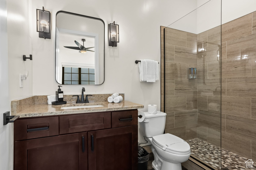 Bathroom featuring ceiling fan, an enclosed shower, vanity, and toilet