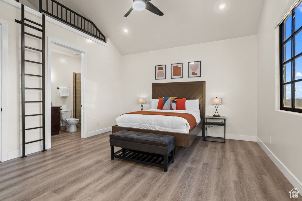 Bedroom with high vaulted ceiling, ceiling fan, connected bathroom, and light hardwood / wood-style floors