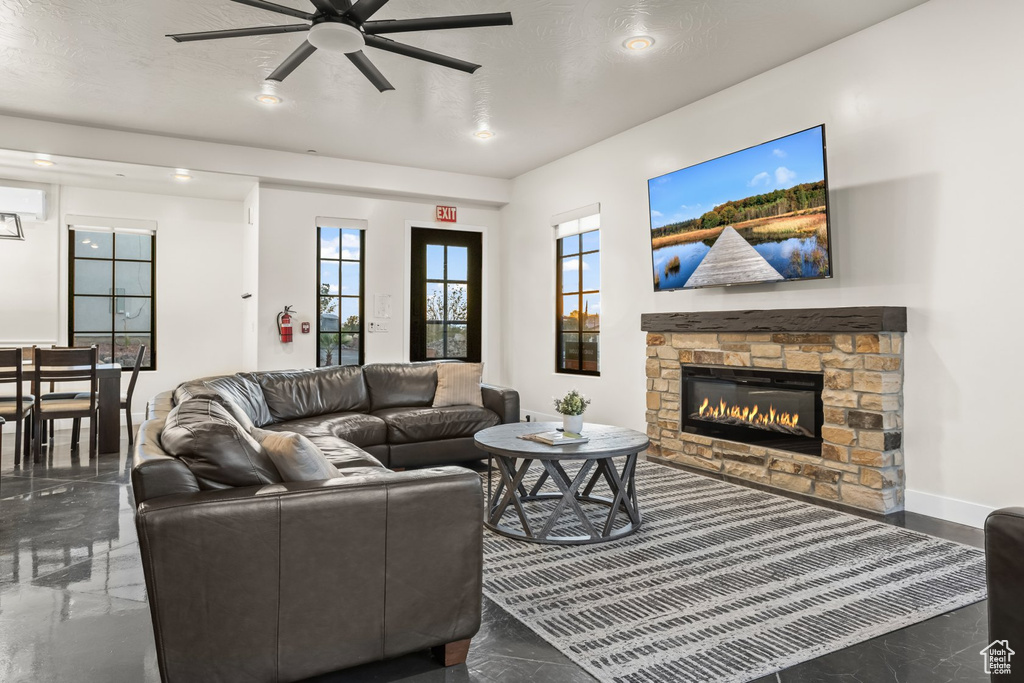 Living room featuring ceiling fan, a stone fireplace, and a textured ceiling