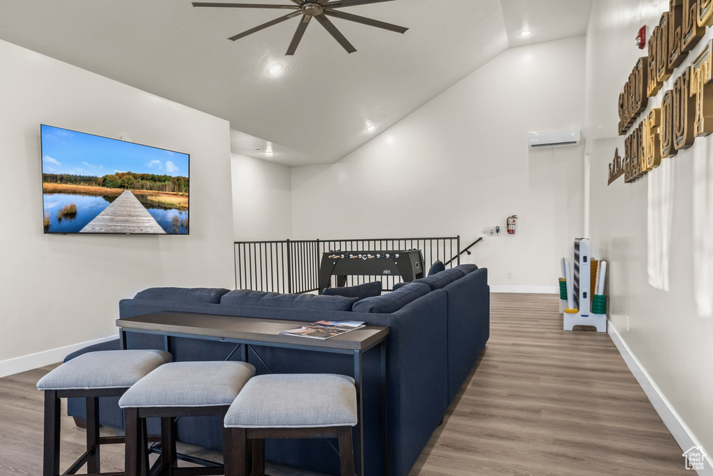 Living room featuring ceiling fan, hardwood / wood-style flooring, vaulted ceiling, and a wall mounted AC