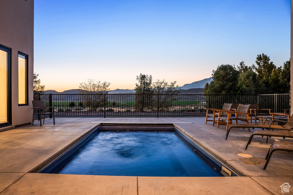 Pool at dusk with a mountain view and a patio