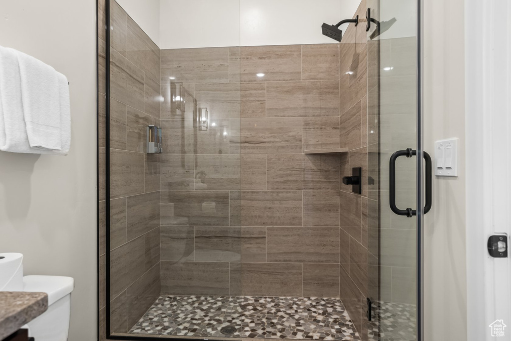 Bathroom with a shower with shower door, vanity, and toilet