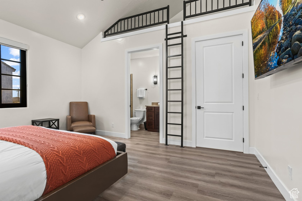 Bedroom featuring ensuite bathroom, high vaulted ceiling, and hardwood / wood-style floors