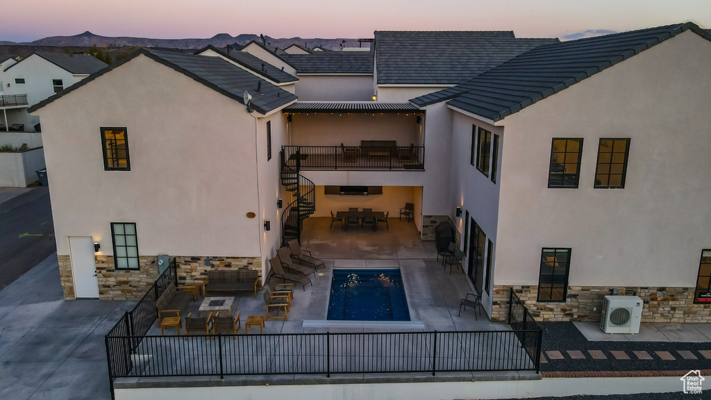 Back house at dusk with ac unit and a patio area