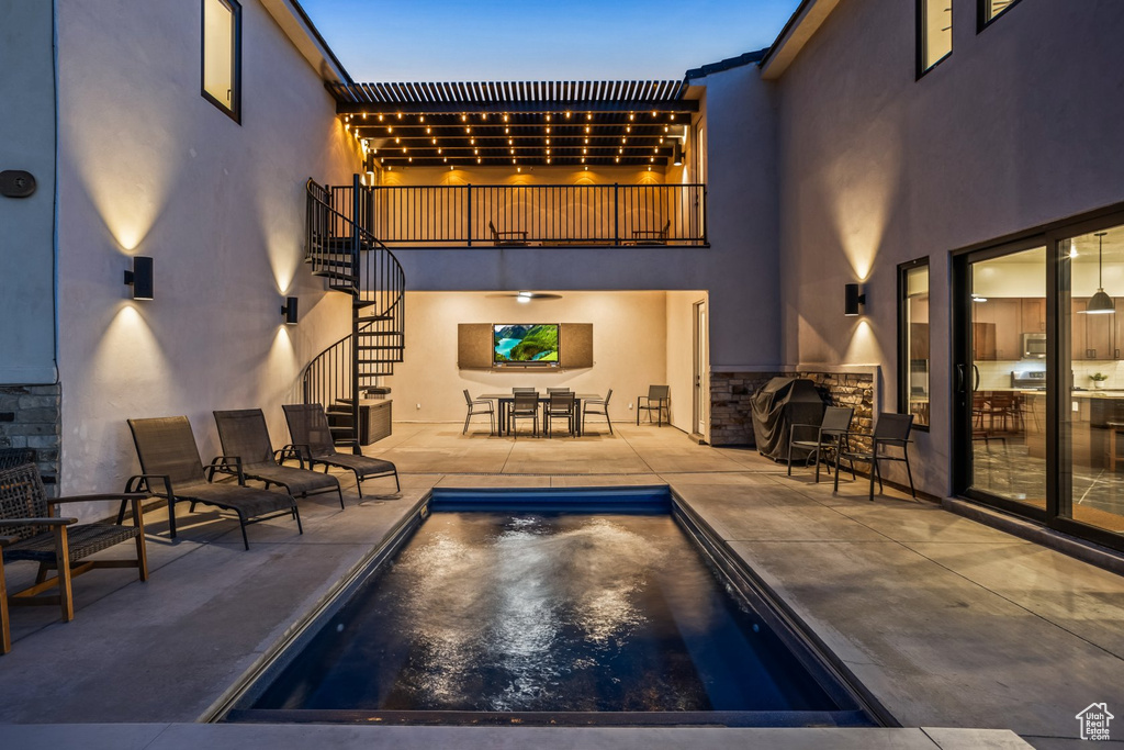 Pool at dusk with an outdoor bar and a patio