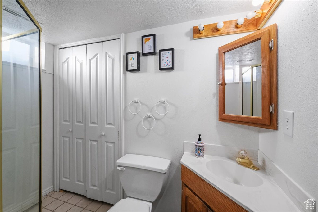 Bathroom featuring toilet, tile patterned flooring, vanity, and a textured ceiling