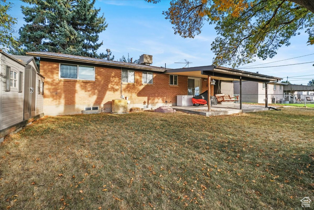 Rear view of house with a yard and a patio