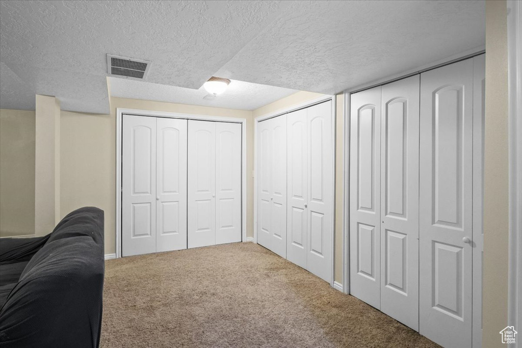 Carpeted bedroom featuring a textured ceiling and two closets