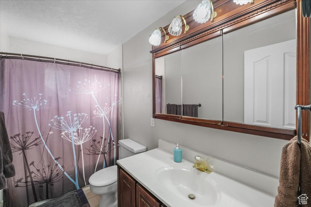 Bathroom with walk in shower, tile patterned floors, vanity, and toilet