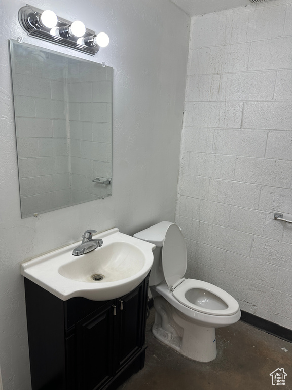 Bathroom with toilet, vanity, and concrete floors