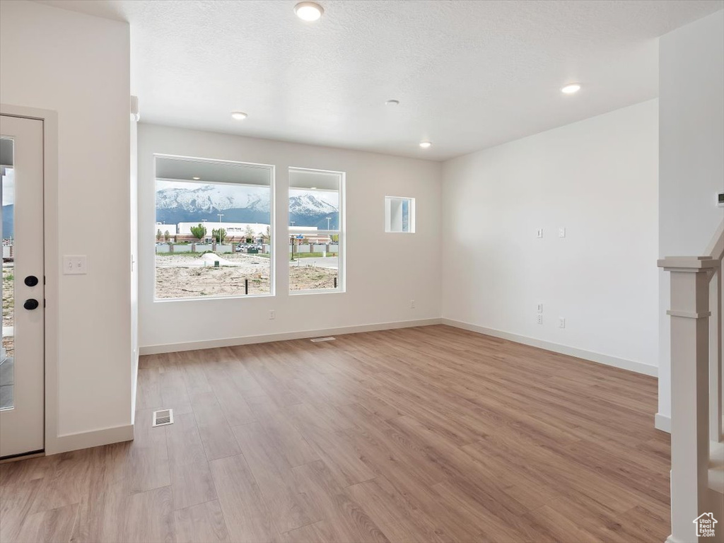 Unfurnished living room with light wood-type flooring and a textured ceiling