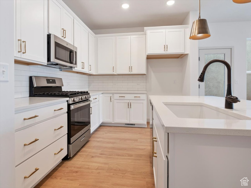 Kitchen with appliances with stainless steel finishes, pendant lighting, sink, and white cabinets