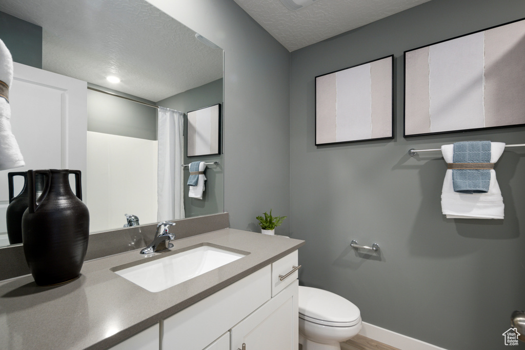 Bathroom with a textured ceiling, vanity, and toilet