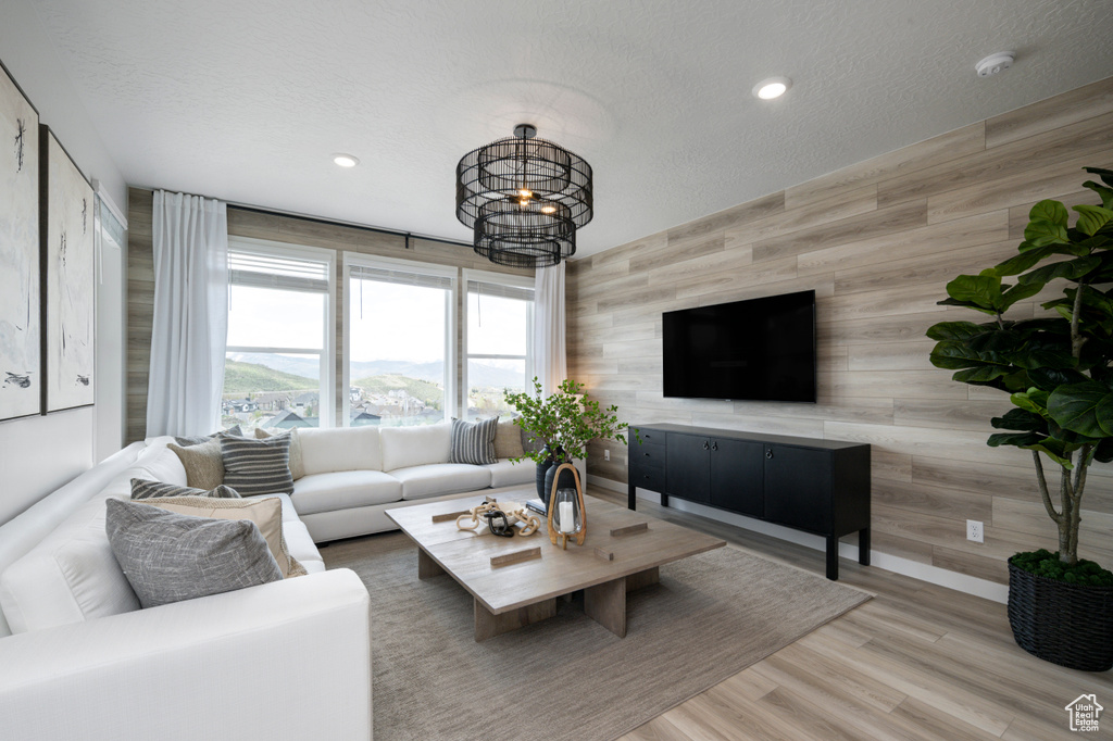 Living room featuring a notable chandelier, wood walls, hardwood / wood-style floors, and a textured ceiling