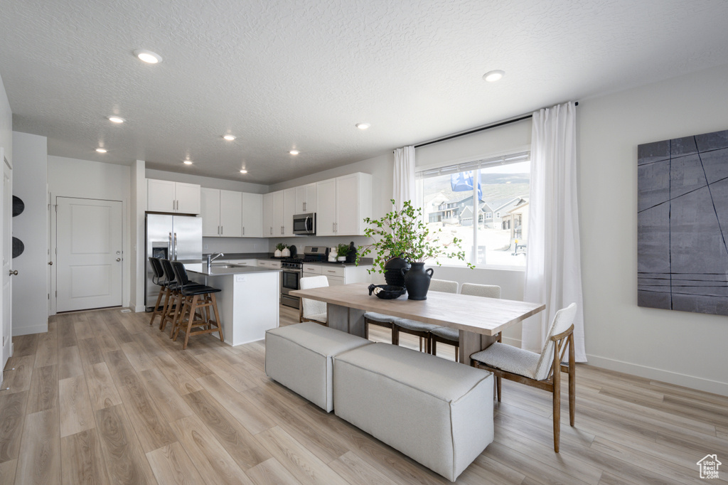 Dining area featuring a textured ceiling, light wood-type flooring, and sink