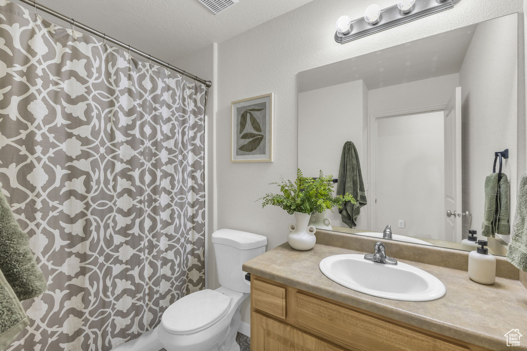 Bathroom featuring vanity, toilet, a textured ceiling, and a shower with shower curtain