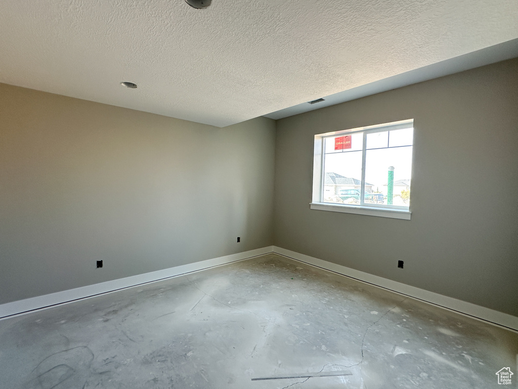 Spare room featuring a textured ceiling and concrete flooring