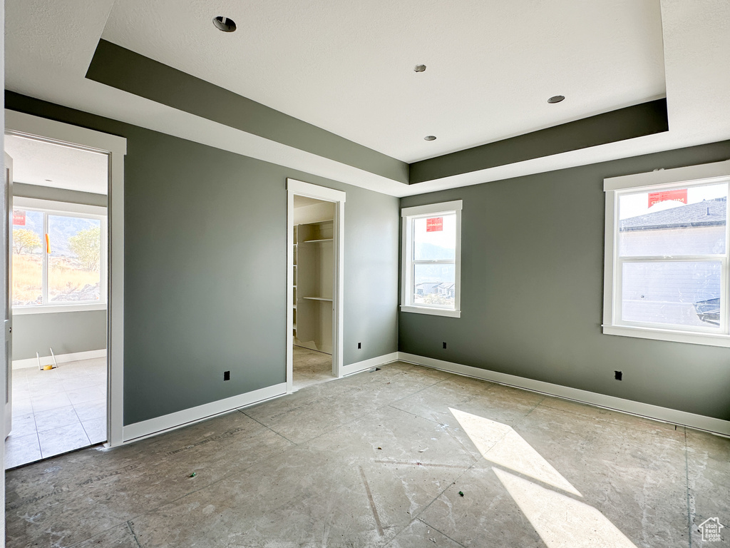 Unfurnished bedroom featuring multiple windows and a walk in closet